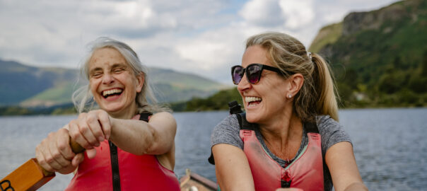 Two women rowing on a lake wearing red boyancy vests. They are staying healthy over 45 with exercise and nutrition.