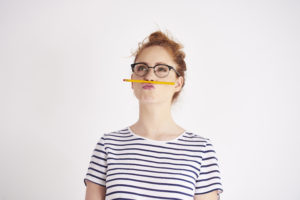 Bored woman procrastinating by balancing a pencil on her lip