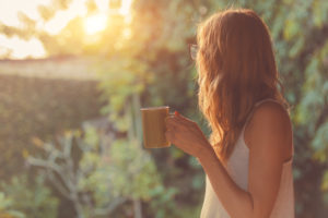 Cute girl working on her mindset enjoying morning coffee on the porch.