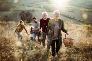 Multi-generational family walking up a hill with picnic basket