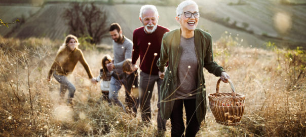 Multi-generational family walking up a hill with picnic basket