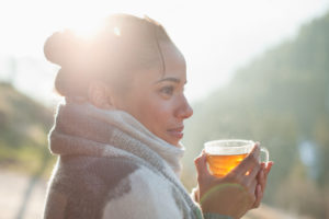 Close up smiling woman in a scarf holding a hot drink