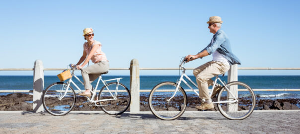 Happy casual couple moving well going for a bike ride on the pier
