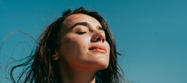 Headshot of pretty young woman against a blue sky. Clearing her brain fog.