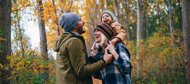 Happy, healthy family of three, in autumn woodland.