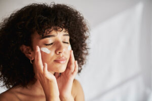 Atopic eczema (also known as atopic dermatitis) is an inflammatory condition that affects people of all ages. Image of young black women moisterising her face.
