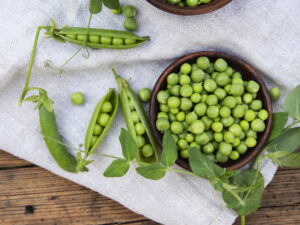 Fresh green peas in a ceramic bowl, pods, on an old wooden surface. Replacing processed red meat from your diet with beans, peas and nuts may help lower dementia risk.