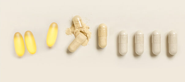 Overhead flatlay of a selection of Bio-effective nutritional supplement capsules against a beige background.